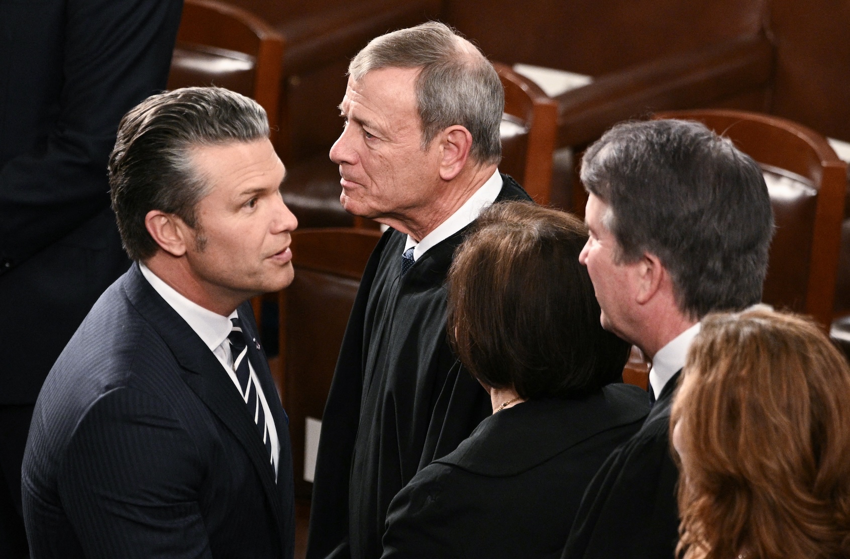 US Secretary of Defense Pete Hegseth shakes hands with Associate Justice Brett Kavanaugh as Chief Justice John Roberts walks by before the arrival of President Donald Trump for the State of the Union address in the House Chamber of the US Capitol in Washington, DC, on February 24, 2026. (Photo by Brendan SMIALOWSKI/Getty Images)