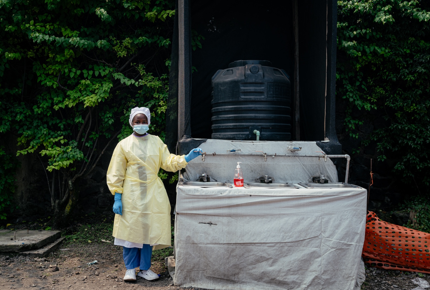 A health worker, wearing single-use protective clothing and a surgical cap, stands at a checkpoint where she oversees hand washing and temperature screening for all visitors and patients entering Kyeshero Hospital, as part of Ebola prevention measures in Goma on May 18, 2026. (Photo by Jospin Mwisha / AFP via Getty Images)