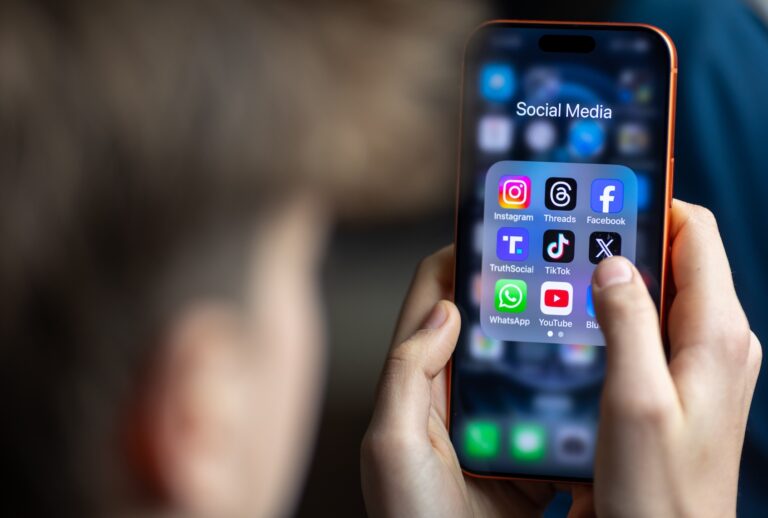 A 14-year-old boy holds an iPhone screen displaying various social media and messaging apps. (Photo by Anna Barclay/Getty Images)
