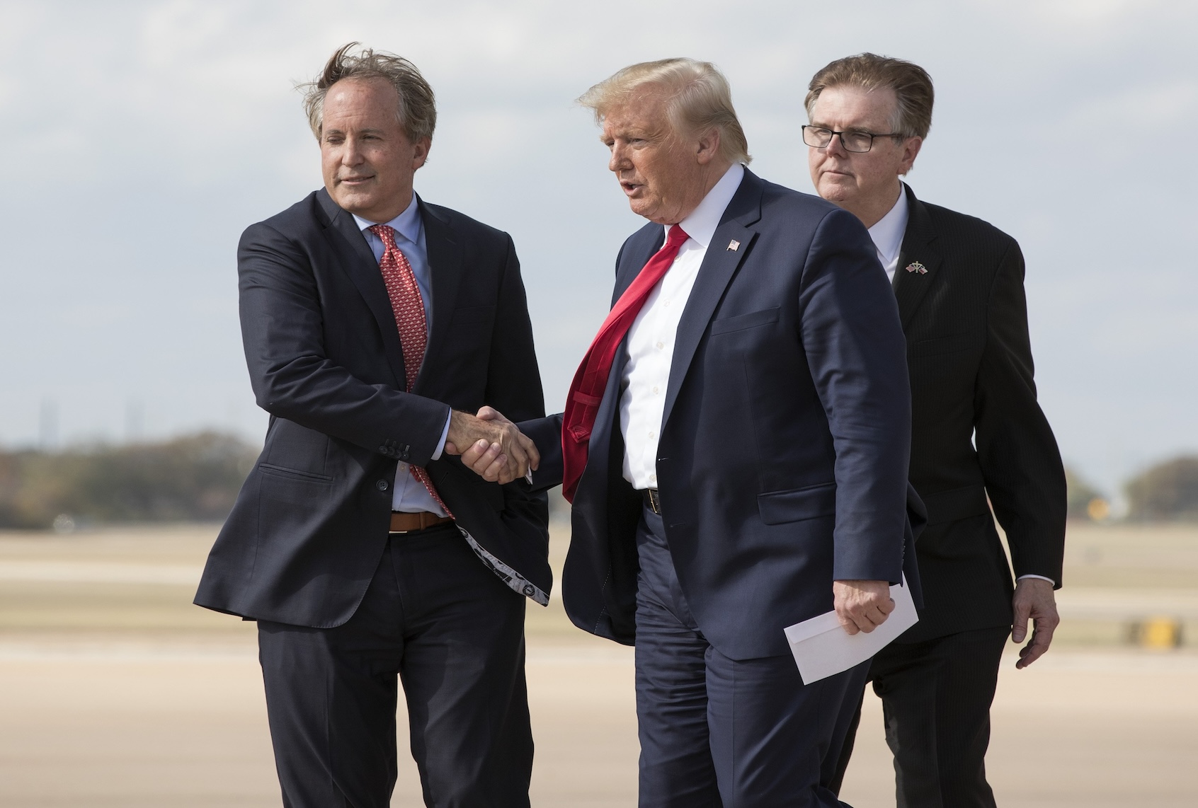 President Donald Trump is greeted by Texas Attorney General Ken Paxton, left, and Lt. Gov. Dan Patrick as he arrives on Air Force One at Austin-Bergstrom International Airport on Wednesday November 20, 2019. (Jay Janner/The Austin American-Statesman via Getty Images)