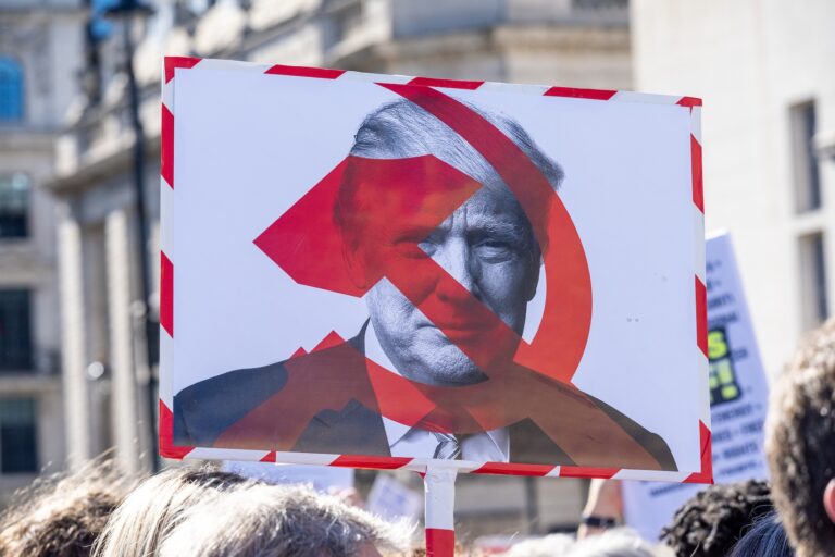 A protester holds a placard with the US President, Donald Trump on it with the symbols of the Soviet Union a sickle and a hammer during the 'Hands Off!' demonstration. Hundreds of demonstrators, including a large number of Americans and Canadians living in London, gathered on the Trafalgar Square to protest against President Donald Trump, Elon Musk and the policies of the Trump administration. (Photo by Krisztian Elek/SOPA Images/LightRocket via Getty Images)