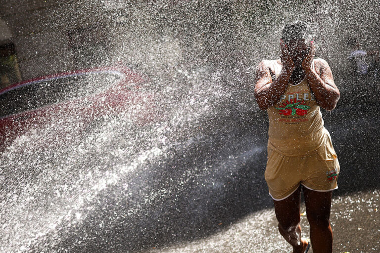 A woman cools off at an fire hydrant in the New York City area amid a severe heat dome. The extremely dangerous weather is affecting nearly half of Americans this holiday weekend. (CHARLY TRIBALLEAU / Getty Images)