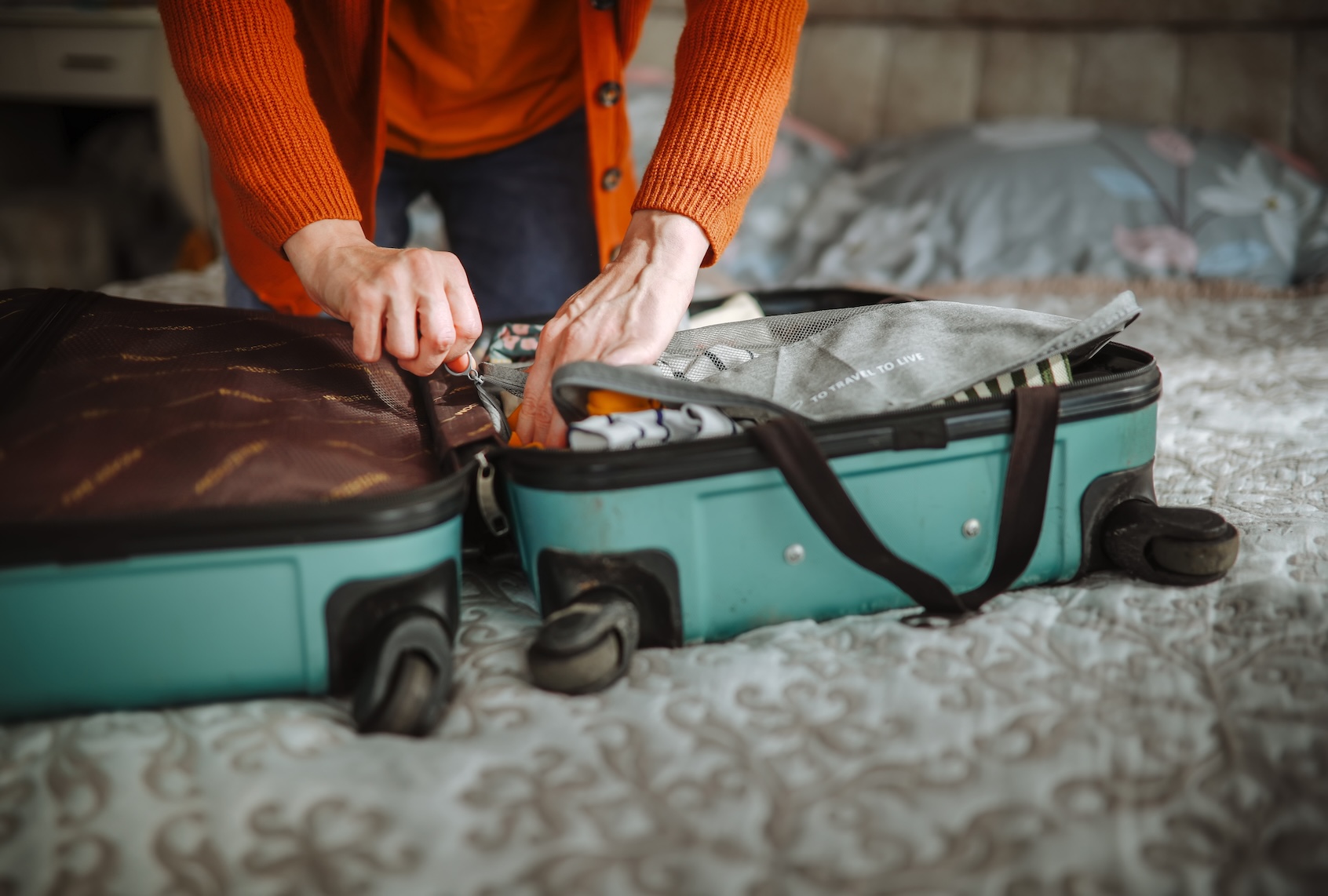 Middle-aged woman in glasses and a cardigan packs a suitcase for a trip. (Natalia Lebedinskaia via Getty Images)