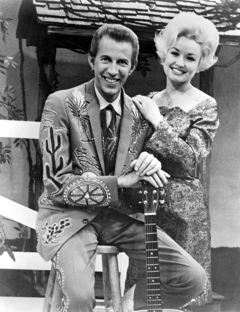 Dolly Parton and Porter Wagoner stand on the set of "The Porter Wagoner Show," circa 1967. Wagoner is wearing a Nudie Suit designed by Nudie Cohn of Nudie's Rodeo Tailors.