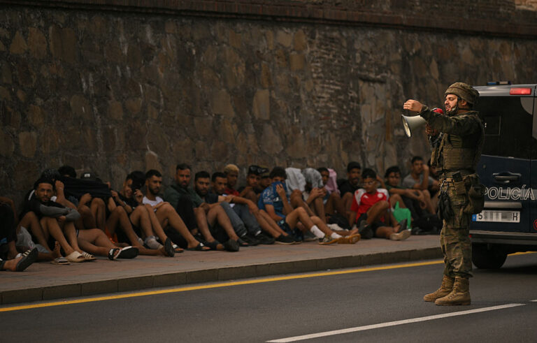 A Spanish soldier speaks to migrants prior to escorting them back to Morocco, in Spain's north Africa's Ceuta enclave. At least 67 people have died in a recent surge of migrant crossings, and most of the 60,000 migrants who entered Ceuta have already returned to Morocco. (JORGE GUERRERO / Getty Images)