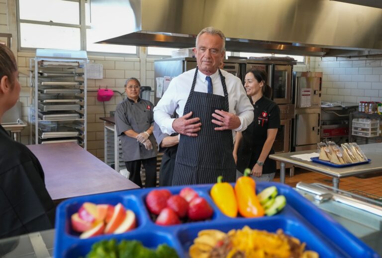 U.S. Health and Human Services Secretary Robert F. Kennedy Jr. puts on his apron before helping to serve lunch during a tour of the kitchen at Cunningham Elementary School in Austin (Jay Janner/The Austin American-Statesman via Getty Images)