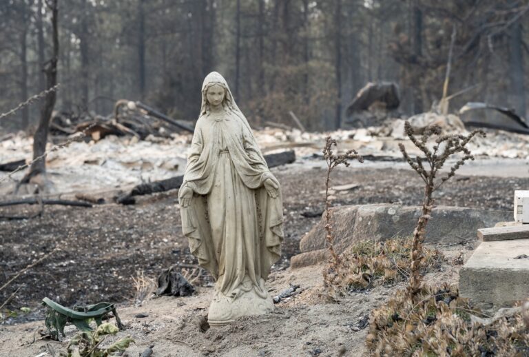 A Virgin Mary statue remains untouched in front of a burned out residential home in the Balboa neighborhood of Spokane, Washington, on August 2, 2026. Fast-moving fires left a trail of destruction in the northwestern US city of Spokane on Sunday, with officials reporting hundreds of structures reduced to cinders. (Photo by Erick Doxey / AFP via Getty Images)