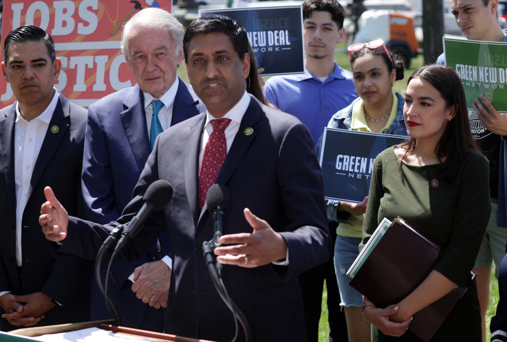 A photo of Rep. Ro Khanna, D-Calif., standing at a microphone outside along with Rep. Alexandria Ocasio-Cortez and other elected officials