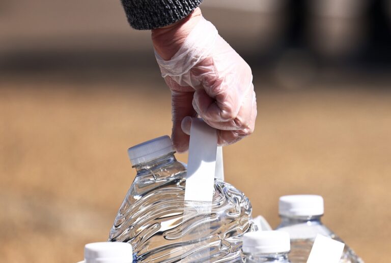 A volunteer grabs a gallon of water at a water and food distribution drive held by College Hill Baptist Church and the World Central kitchen on March 07, 2021 in Jackson, Mississippi. Residents in parts of Jackson, Mississippi, where 80% of the residents are Black, have been without running water since mid-February after the city was hit by back-to-back winter storms. (Photo by Michael M. Santiago/Getty Images)