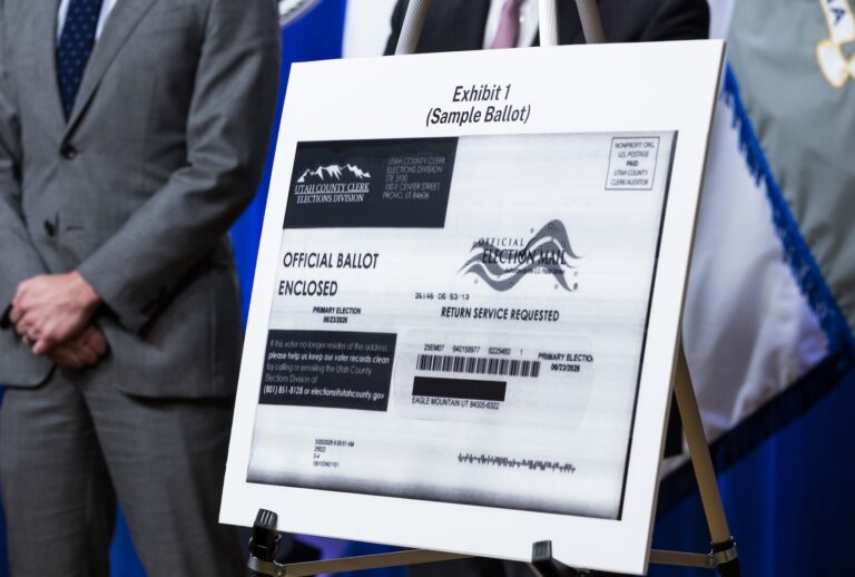 A poster showing a sample mail-in ballot is displayed as U.S. Acting Deputy Attorney General Trent McCotter speaks during a press conference at the Department of Justice on September 22, 2026 in Washington, DC. McCotter announced that an election worker in Utah has been indicted for allegedly throwing away ballots. (Photo by Finn Gomez/Getty Images)