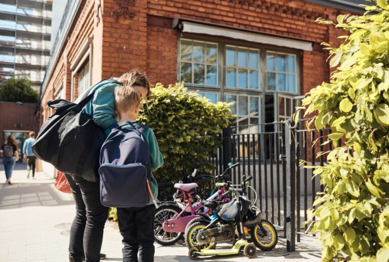 Woman standing with her son at the school gate on a sunny day (Maskot/Getty Images)